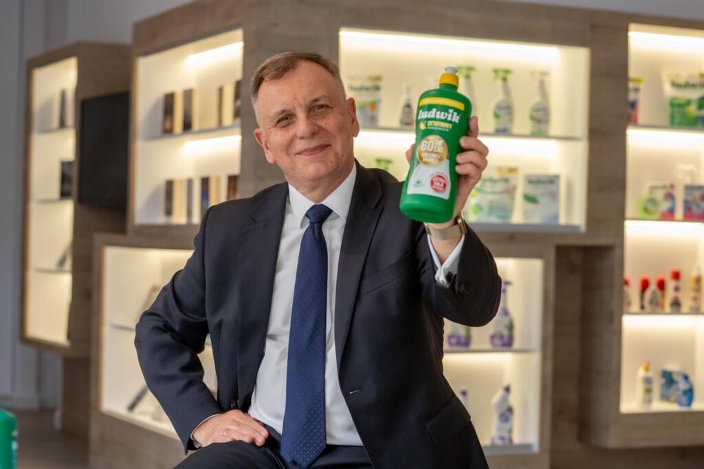 Man in a suit holding a bottle of Ludwik in a production hall