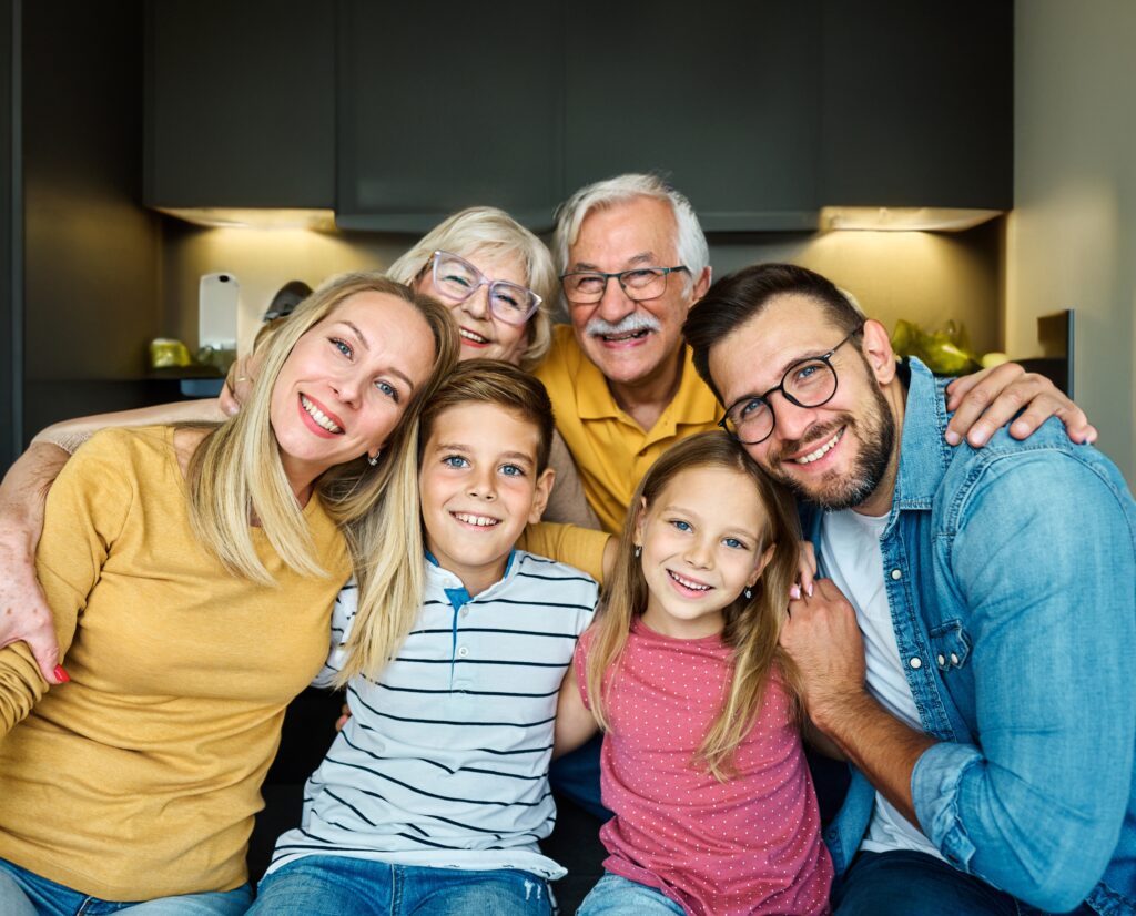 Three generations of a family hugging in the kitchen